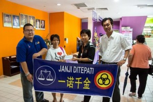 Sarawak Social Welfare Department's Assistant Welfare Officer Madam Chai (2nd from right) hands over the cheque to Pui Nyet Fong (2nd from left) witnessed by SUPP Central Youth Secretary General Wilfred Yap (1st right) and youth member Isaac Lee (1st left).