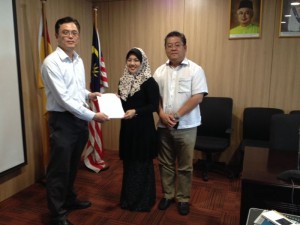 Tan receiving the voucher today with Penghulu Lim Eng Huat looking on.