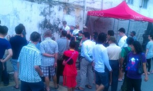 Crowd watch Ernest working under a canopy