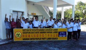 在挂上新牌匾前，李进兴(左7)率领执委党员高举一马手势。